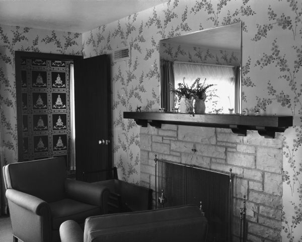Fireplace in the Westye Bakke house at 4818 Odana Road (now 4817 Sherwood Road). There is a mirror over the fireplace, and two chairs are arranged in front. A door is open to a hallway in the background.