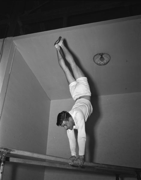 John Matheus, captain of the University of Wisconsin gymnastics team, working out on the parallel bars. He captured two firsts and two thirds in a meet with the University of Chicago.