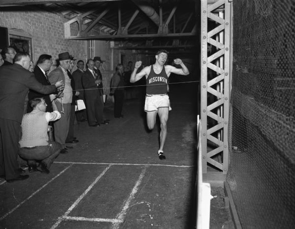 Jim Urquhart crossing the finish line as he sets the annex record for the two-mile indoor run at the University of Wisconsin Athletic Annex, 702 Langdon Street.
