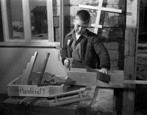Gene Ryberg, member of Silver Badgers 4-H Club, using a saw while working on a handicraft project.