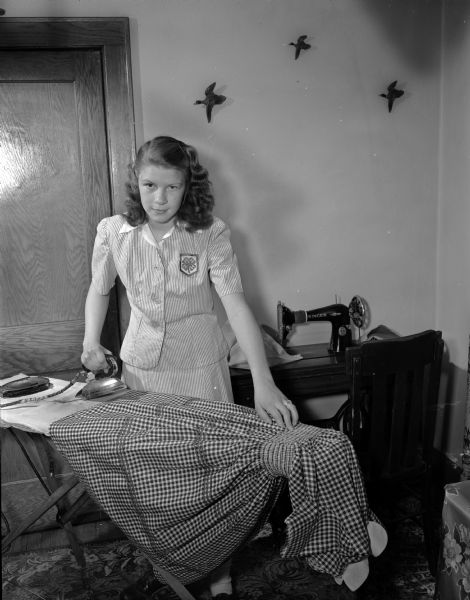 Peggy Meyer, member of the Silver Badgers 4-H Club, ironing a dress she is sewing.