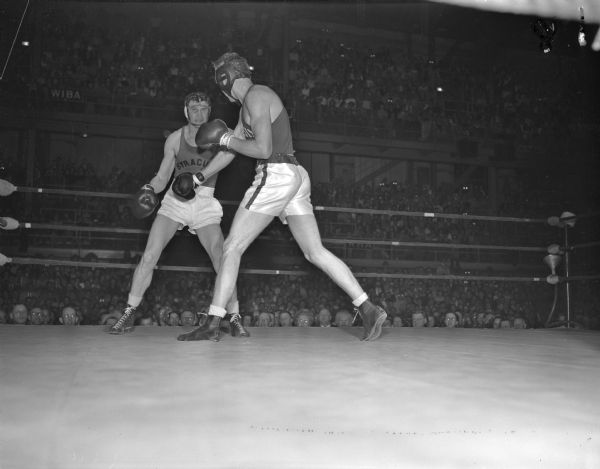 University of Wisconsin light heavyweight boxer, Gene Fleming lands a blow to the jaw of Syracuse University's captain, Ray Fine.