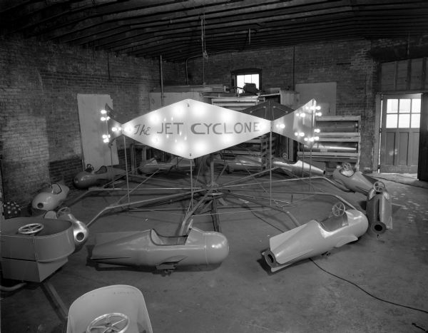 A carnival ride, "The Jet Cyclone," in the process of construction in a garage.