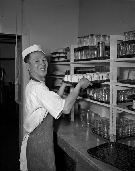 Chuan-Yen Liu, a University of Wisconsin graduate student in economics, working at the Truax Field cafeteria. The students at the University of Wisconsin have financial need due to the war in China and the spiral of inflation. Students who were supported by the Nationalist government have had no word concerning their allotments. The Reverend James R. Love, executive secretary of the Madison Council of Churches, inspired the organization to inquire into the need for funds, collect funds, and through the Chinese Student Organization, to determine which students were in need.
