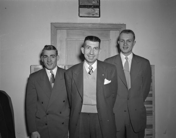 Pictured standing between two basketball team members is University of Wisconsin basketball coach Harold "Bud" Foster. Standing on the left is senior Doug Rogers, captain of the 1949 team, and on the right is junior Don Rehfeldt, who was named Wisconsin's most valuable player.