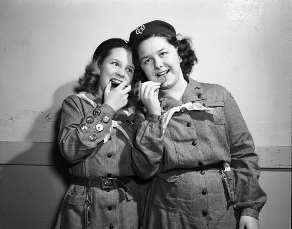 Nancy Hockett and Patricia Rinden, two Girl Scouts from Troop 46 at East Jr. High School, nibble cookies  in anticipation of their project to sell cookies for the benefit of the Scout camp fund. 