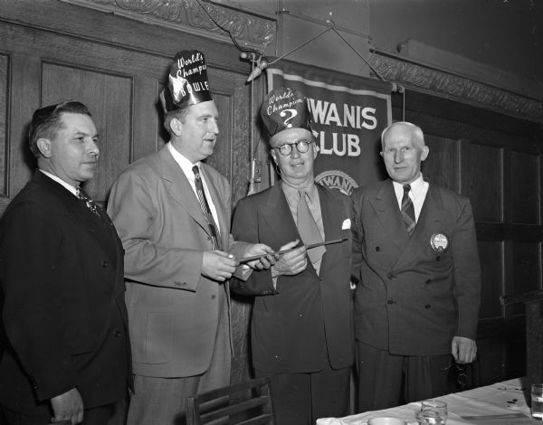 Connie Schwoegler, world's champion bowler, and Roundy Coughlin, <i>Wisconsin State Journal</i> columnist, wearing "world champion" hats at a Kiwanis Club meeting at the Park Hotel. Two unidentified men are also in the group portrait.