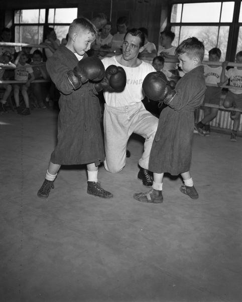 Two brothers, Dick and Bobby Johnston, posing with Don Dickinson during the Little Badgers boxing classes at the University of Wisconsin fieldhouse.