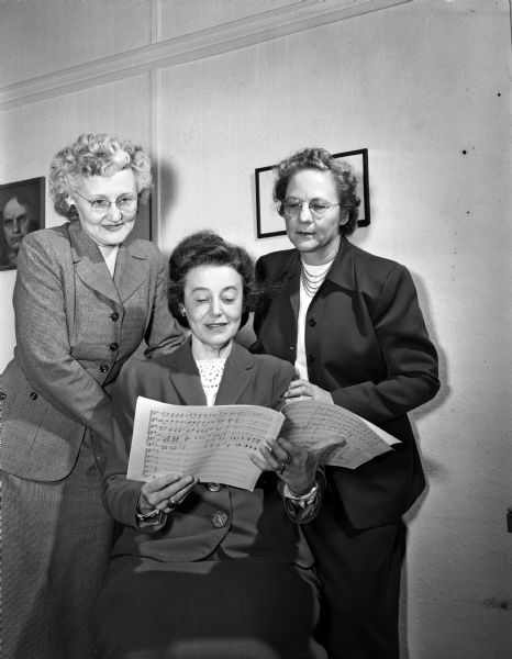 Two Madison women composers prepare for the introduction of their songs by the University of Wisconsin's Women's Chorus at their spring concert. Pictured left to right: Assistant Professor of the music school Helen S. Thomas Blotz, chorus conductor; Constance Maclean Champion, seated at the piano; and Helen Piper Law.