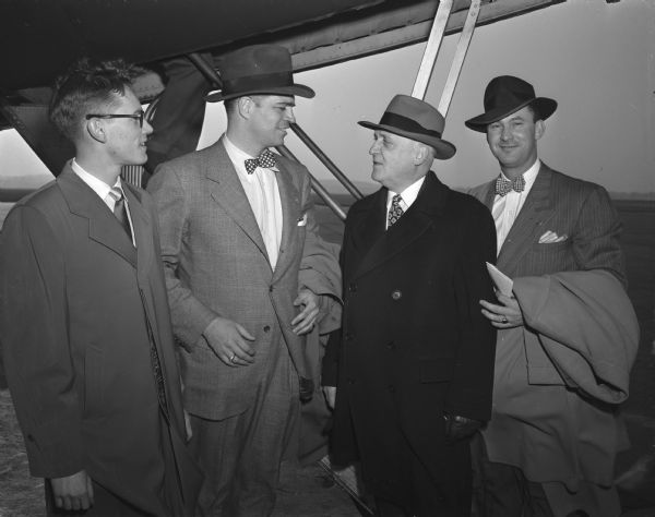 UW President E.B. Fred (second from right), and Student Board president Tom Englehardt (at left) welcome Michigan Governor G. Mennen Williams (second from left) and his aide, Sam McIntire (at right) upon their arrival at the Truax Field airport. Gov. Williams will be a speaker at a campus symposium on student government in higher education.