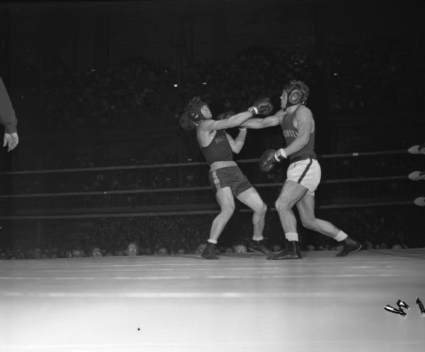 University of Wisconsin boxer Glenn Nording (right) landing a right to the chin of Minnesota boxer Dick Newberg in their bout at the fieldhouse.