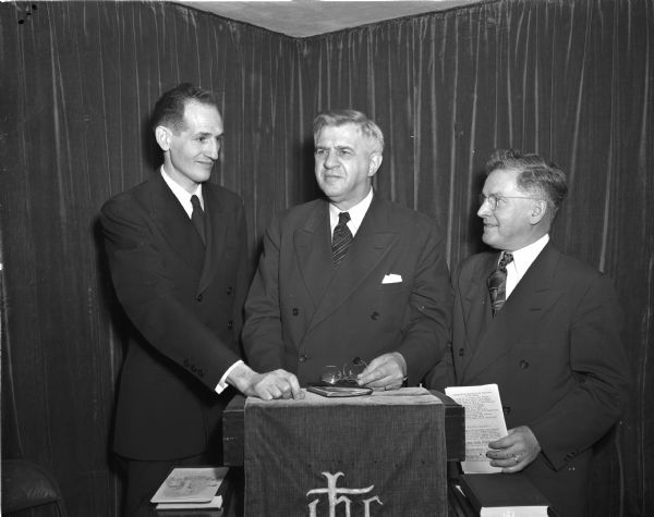 The Reverand Harold Huff (left), pastor; Bishop H. Clifford Northcott (center), and Reverand W. Ross Connor (right) leading a special morning service to dedicate the West Side Community Methodist Church at the corner of Mineral Point Road and Larkin Street. The ceremony marked the first anniversary of the founding of the church.