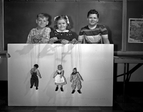 Jimmy Fladen, Christine Mercer, and Paul Vincent manipulate Punch and Judy marionettes in the orthopedic department at Washington School, 545 West Dayton Street.
