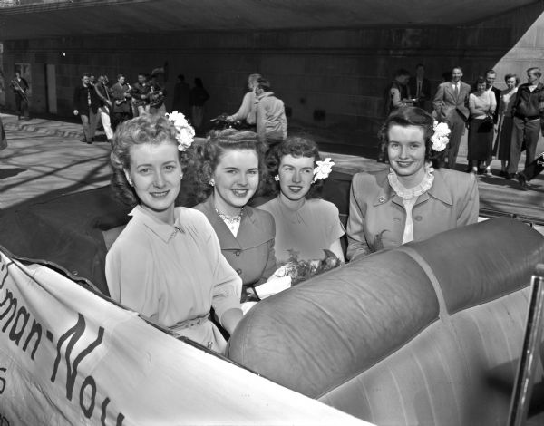 Miss America of 1948, BeBe Shopp, second from left, rides in the back seat of a convertible with Jaenne Faber, Suzaanne Wheeler, and Anne Barber. BeBe Shopp was brought to Madison to reign as queen of the Faville-Gilman-Noyes houses formal Tophatter dance in the Park Hotel on Saturday night.