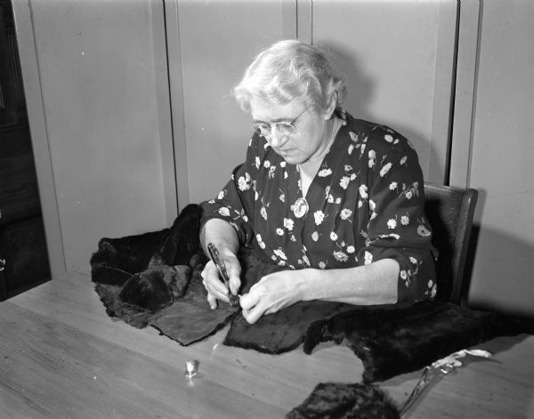 Mrs. Moses W. (Edna) Smith in the process of remodeling her fur cape at a fur remodeling class at the Madison Vocational School.