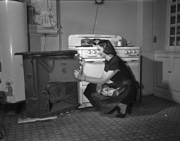 Mary C. Donahoe inspecting an antique gas range next to new model at the Madison Home Appliance and Radio Show in the East High School gymnasium.