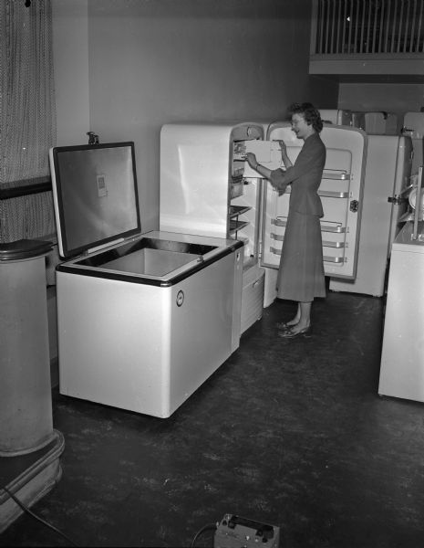 Joanne Johnson looking at a new style ice tray in a refrigerator with a freezer unit next to it at the Madison Home Appliance and Radio Show in the East High School gymnasium.