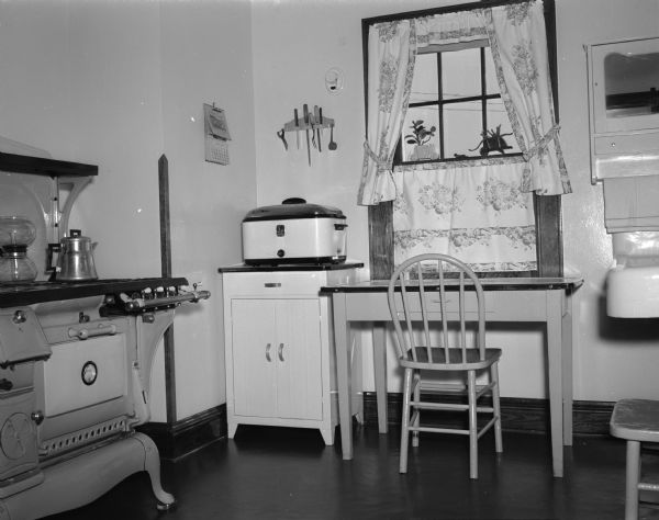 Kitchen in the Harry R. Sharpe family farm home located on the University of Wisconsin poultry research farm, 5101 Mineral Point Road. An old gas range stove is along the wall on the left.