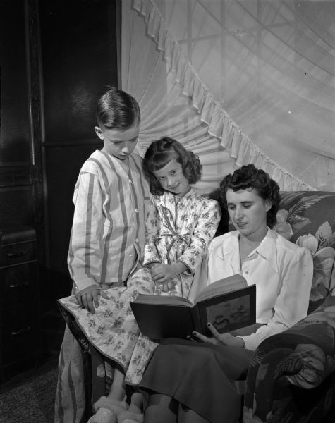 Tim, 8, and Maureen, 6, listen quietly as their mother, Mrs. Mark Schaefer, reads a bedtime fairy tale at their home on Mineral Point Road. Mrs. Schaefer belongs to the Middleton homemakers center which is served by the Wisconsin cooperative extension system.