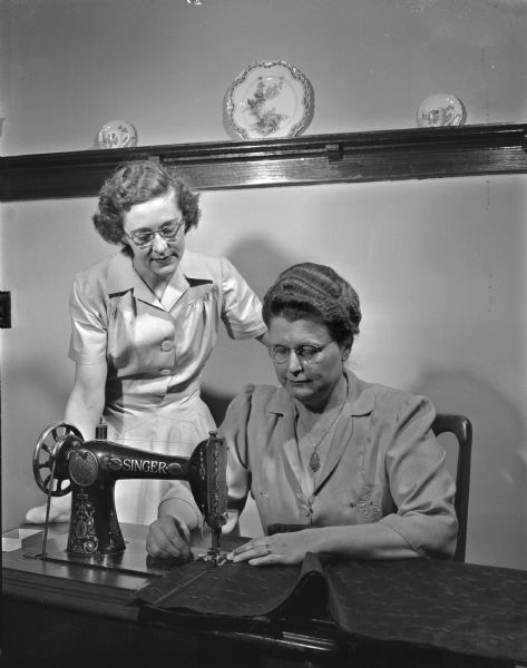 Mrs. C.H. Nordberg, 44 Nygard Street, looks on as Mrs. Frank G. Miller, 1950 Koster Street, demonstrates her sewing machine skills. They are both members of the Oregon Homemakers Center which is served by the Wisconsin Cooperative Extension System.