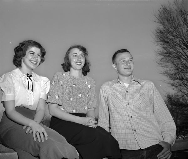 Three West High School senior honor students sitting and standing outdoors. Left to right: Elaine Hawley, Lou Ann Jones and Douglas Koepcke.