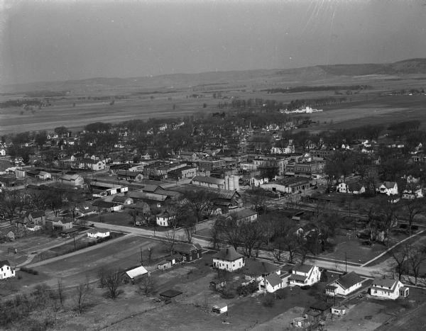 Aerial view of Spring Green. Houses and commercial buildings are in the foreground and a rural area is in the background. Hills are in the distance.