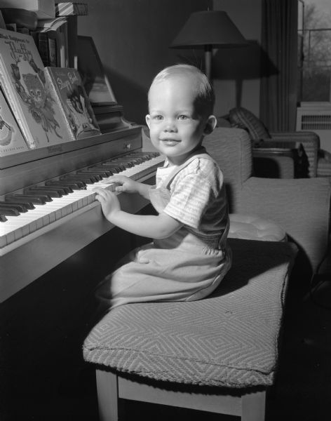 Two-year-old James William Geisler, the son of Mr. & Mrs. James Geisler of 1632 Monroe Street, sits at a piano for a portrait taken for National Baby Week.