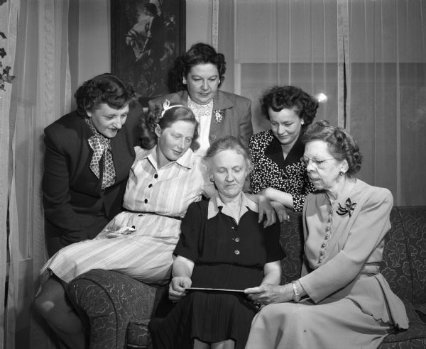A group of club women are discussing plans for a community project in the village of La Valle. Seated in the middle is Mrs. L.O. Waller, president of the La Valle Literary Club. Grouped around her, left to right, are Mrs. Merwin Miller, vice-president; Mrs. Edward Gardner, president of the Homemakers Club; Mrs. Larry White, president of the American Legion Auxiliary; Mrs. M.H. Mueller, president of the Zion Lutheran Church Ladies Aid Society; and Mrs. Henry McKnight, vice-president of the La Valle Mothers Club.