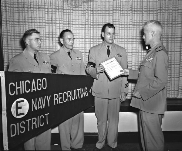 Navy recruiters of the Madison sub-station are presented a banner and certificate of merit for leading the Chicago area district in number of enlistments for the first quarter of the year. Pictured left to right are: Chief E.D. Gormel, Iron Mountain, Michigan; Chief A.J. Ihde, Wisconsin Dells; Chief G.E. Zile, Madison, and Captain Jack E. Hurff, senior naval officer in the Madison area and commandant of the University of Wisconsin NROTC, who presented the award.