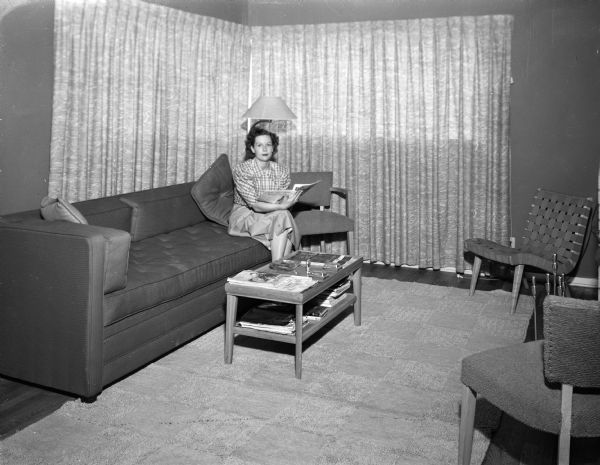 The living room of the home of Mr. and Mrs. Keith Roberts, 13 South Midvale Blvd., one of four homes designed and constructed by Marshall Erdman for war veterans with small families.  Mrs. Roberts is pictured seated on a sofa in the living room.