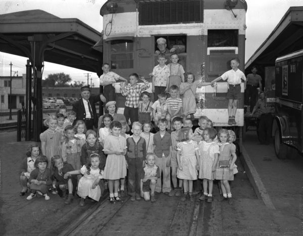 Thirty-six Verona first and second grade pupils rode the Chicago and North Western train from Verona to Madison, for twenty-two it was a first train ride. The engineer, Dill Dickens, encouraged the children to get in front of the engine for the picture and helped the boys climb on the front of the train. Their study of rransportation culminated in the train ride on the single coach train service from Lancaster to Verona and Madison.