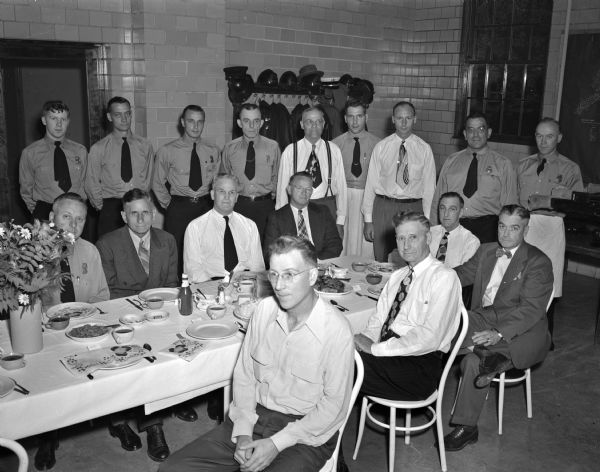 Retirement party for Stanley Oldham at the No. 7 fire station, 2410 Monroe Street. Standing, left to right, are: firemen William Ferger, Thomas Barry, Marvin Kammer, Inspector Harry Page, Arthur Lewis, Robert Couture, Walter Gavin, H.J. Holzwarth, and Lieut. Phillip Narf. Seated, clockwise around the table, are: Harry Smith, retired fireman Richard Lawrance, Assistant Chief Leonard Sime, Captain Howard Comstock, Oldham, Chief Edward J. Page, retired Harvey E. Johnson, and Captain Derrel Lawrie.
