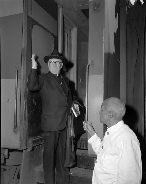 Bishop William P. O'Connor of the Madison Catholic diocese as he boards a Chicago-bound train on the first leg of his trip to Rome, where he will report to Pope Pius XII on the condition of the diocese. From Chicago, the bishop will travel to New York by train where he will board the S.S. Atlantic for a voyage to Genoa, Italy.