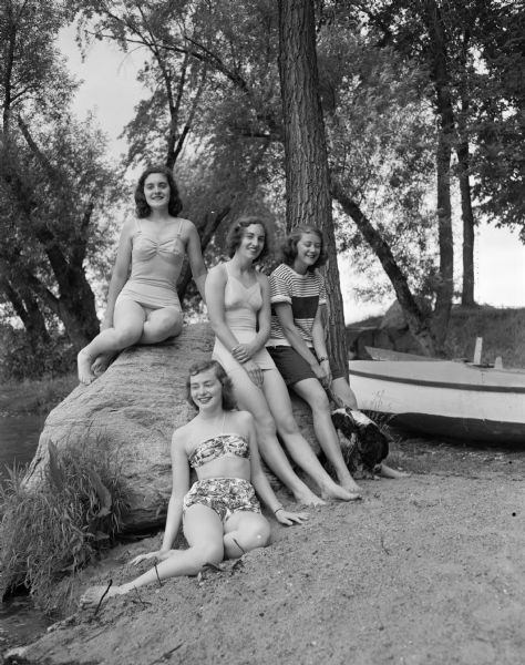 Four Madison teenagers at the Willows swimming beach as they await the opening of city beaches. Seated on the ground is Nancy Fitzgibbon. Nancy Roark is perched on the rock. The other two girls are Marilyn Jones and Lucy Roberts.