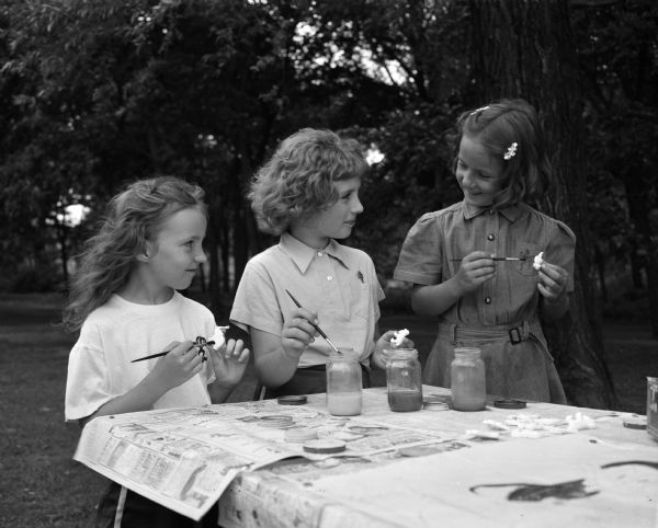 Three girls doing craft work at the Brownie Day Camp at Burrows Park.  Left to right, Barbara Jean Jull, daughter of Mr. and Mrs. George Jull, 2434 East Johnson Street; Anne Marie Hoffman, daughter of Mr. and Mrs. Joseph Hoffman, 1721 Vahlen Avenue; and Gail Sholts, 2812 Dahle Street.