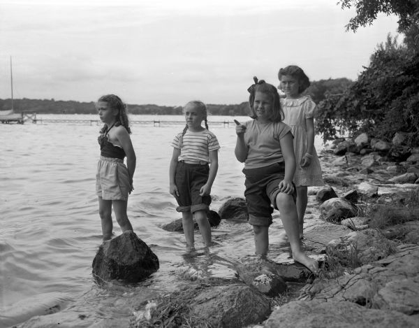 Four girls wading in Lake Mendota. They were attending the Brownie Day Camp at Burrows Park. Left to right: Marilyn Dvorak, daughter of Mr. and Mrs. Alfred Dvorak, 715 Davidson Street; Julie Woerpel, daughter of Mr. and Mrs. Robert Woerpels, Sun Prairie; Linda Elliott, daughter of Mr. and Mrs. Raymond Elliotts, 212 Kensington Drive; and Deanna Mahoney, daughter of Mr. and Mrs. Dean Mahoney, 2018 Rusk Street.