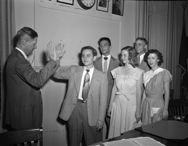 Madison Youth Council officers taking the oath of office from City Manager Leonard G. Howell.  New officers, front row, left to right:  Sherwyn Woods, president; Peggy Huiskamp, corresponding secretary; and Beth Mitchell, recording secretary.  Back row: Bob Schwartz, treasurer; and Dan Peterson, vice-president.