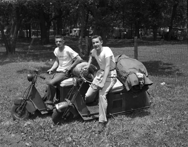 Donald Tormey, left, age 17, and Franklin Conway, age 16, with their motor scooters shortly after completing a 1,300 mile trip to Canada on the bikes.