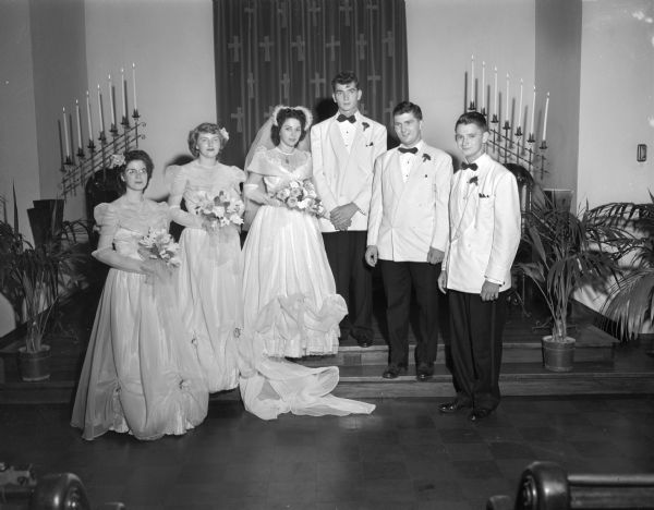 The Huffman-Lewis wedding party in the chancel of First Congregational Church, 1609 University Avenue. Left to right: Mrs. Howard Smith, Kenosha bridesmaid; Donna Jean Jenkins, bridesmaid; Norma Jean Huffman, bride; Donald E. Lewis, groom; Robert Wiggins, best man; and Boyd Croxen, Kankakee Illinois, groomsman.