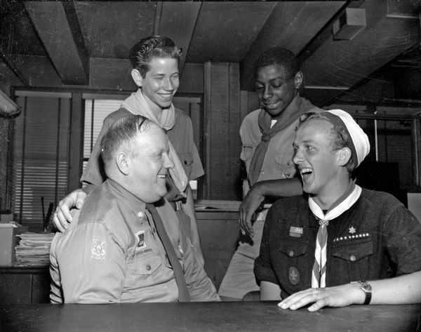 Pictured at right is Harry Thomsen, twenty-one year old Boy Scout from Denmark. Thomsen is spending a few days in Madison visiting friends in the Four Lakes drum and bugle corps. Seated at left is C.H. Beebe, director of the corps. Standing in the rear are Marvin Stitgen, at left, and Charles Harris, at right.