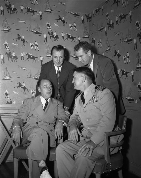 Wisconsin athletic director Harry Stuhldreher, with head coach Ivan Williamson, conferring with their counterparts from the United States Naval Academy, Captain Howard Caldwell and George Sauer. The teams are to play in Madison October 15, 1949.