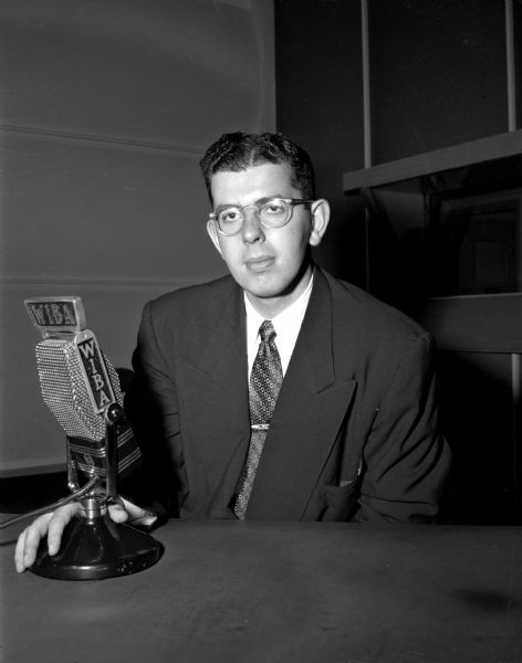 A Soap Box Derby announcer (either Lon Landman or Dwaine Tucker) sitting at a WIBA microphone.