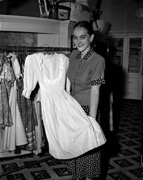 Mrs. Dana J. Dillon, advertising manager for Baron Brothers department store, 14-18 West Mifflin Street, holds a dress from the Baron's children's department. Baron's store is offering an ensemble from the store's children's department as the grand prize to the girl chosen as princess at the Soap Box Derby. All Madison girls between the ages of ten and twelve are eligible to try out for the honor of representing Madison as Soap Box Derby princess.