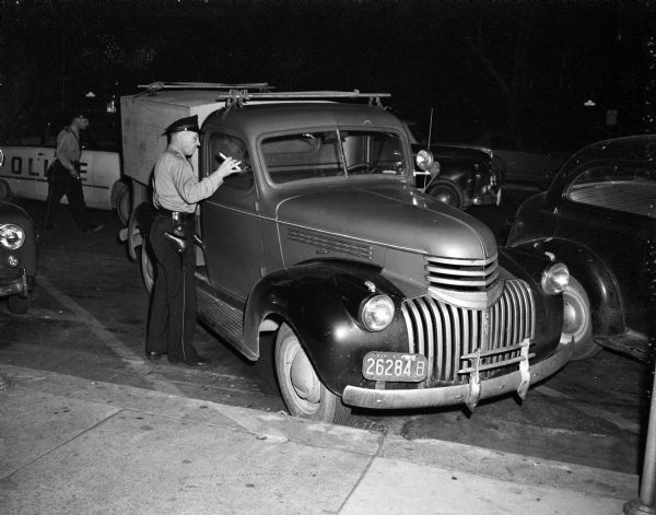 Unidentified police officer inspecting the truck owned by George "Butch" King, suspected killer of Sadie Jackson.