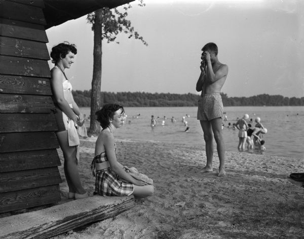 A man taking a picture of two women at the Vilas Park beach.