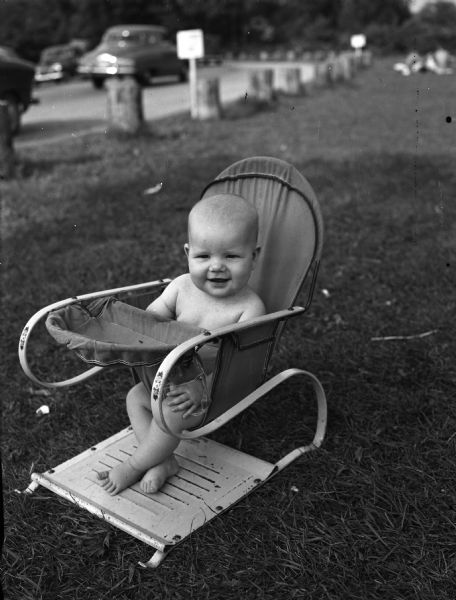 A toddler sits in a bouncy chair at the Vilas Park beach.
