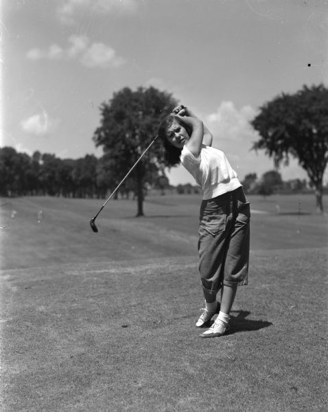 Sixteen-year old Peggy Kral of Shawano Lake's Shalagoco Golf Club, a possible contender for junior honors in the Wisconsin Women's Association tournament, swings a club at Maple Bluff Country Club. Peggy's sister, Mary Louise Kral, is also competing in the tournament being held at the Maple Bluff club.