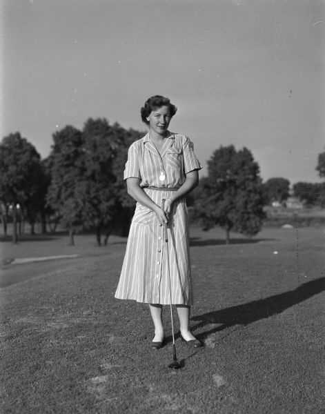 Mrs. John Clauder of Milwaukee poses with a golf club at Maple Bluff Country Club. She is a participant in the Wisconsin Women's Golf Association Tournament at the club and a past tournament champion.