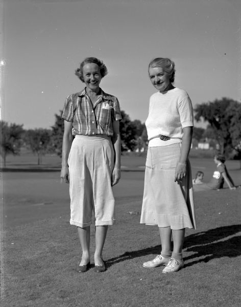 Mrs. Floyd Vlight and Mrs. Vern Bell standing beside each other at Maple Bluff Country Club.  The two women staged the longest match during the Wisconsin Women's Golf Association Tournament, lasting twenty-three holes.