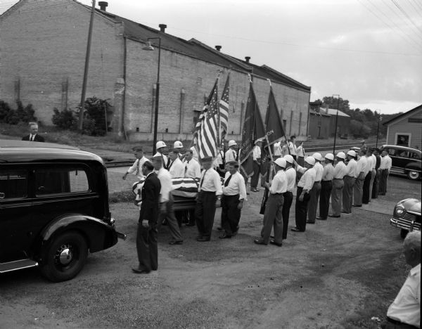 Funeral cortege of veteran Frank "Bud" Willman at the railroad depot in Edgerton.  The cortege included a color guard, Legionnaires and marching men of the Veterans of Foreign Wars.